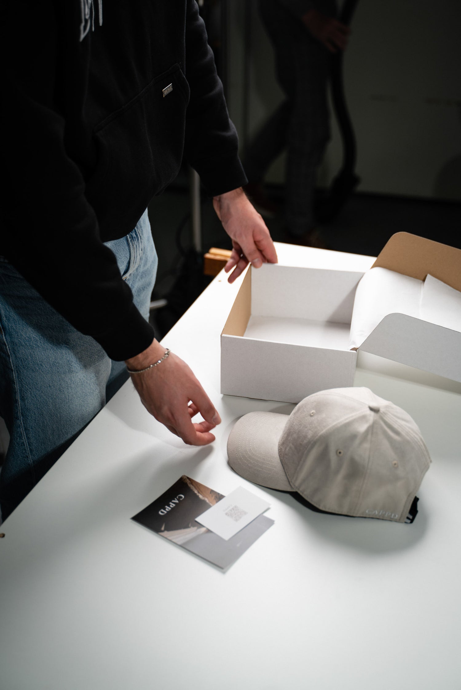 Beige Baseball Cap mit neben einem weißen Karton